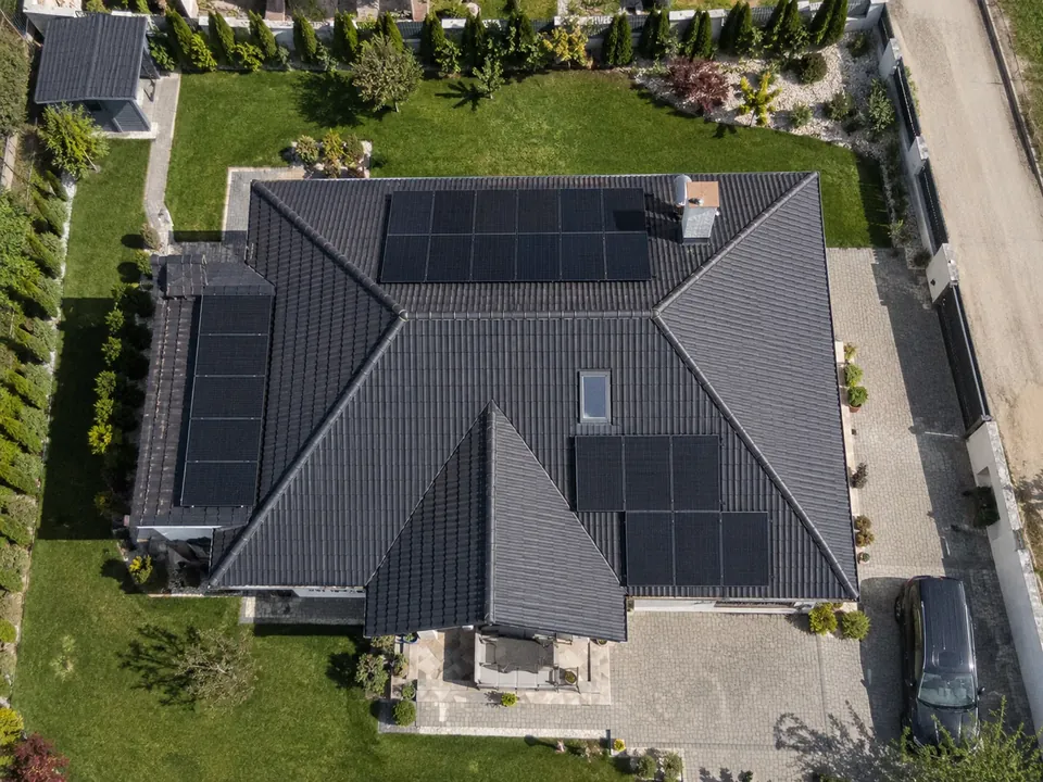 Casă cu sistem fotovoltaic și mașină parcată în curte